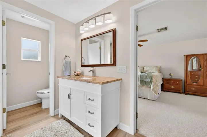 Full bathroom with vanity, ensuite bathroom, light wood-type flooring, and a ceiling fan