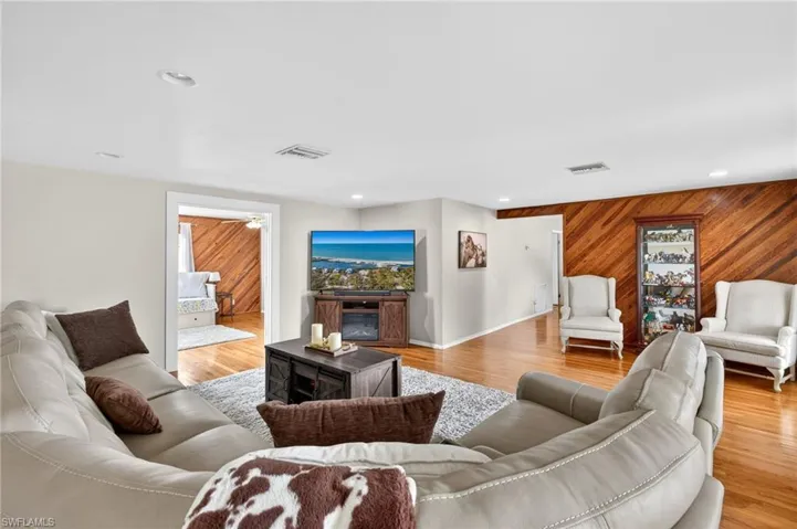 Living room with wood walls, light wood-type flooring, recessed lighting, and a fireplace