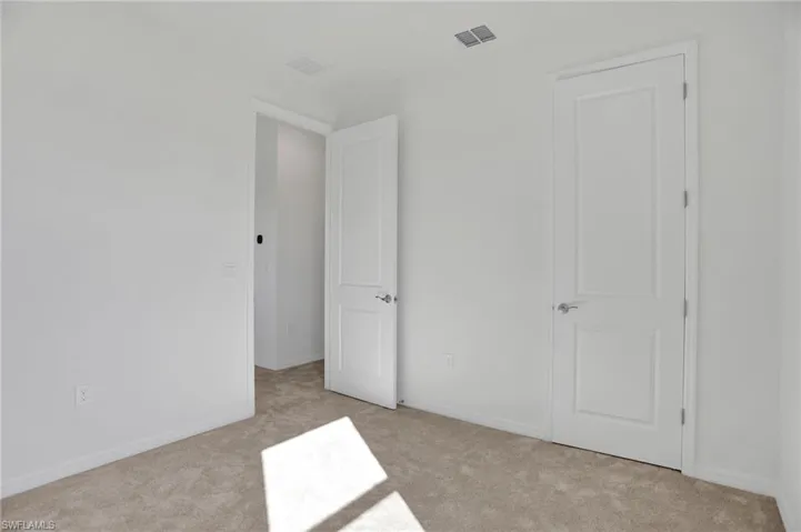 Unfurnished bedroom featuring light carpet and baseboards
