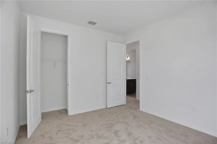 Unfurnished bedroom with light carpet and a closet