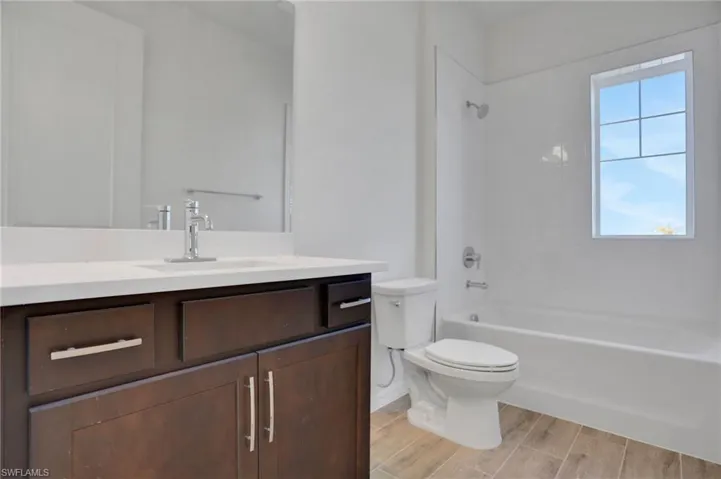 Full bath featuring vanity, shower / bathtub combination, and wood finish floors