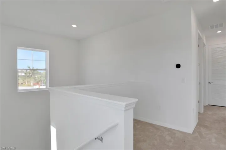 Hallway with light carpet and recessed lighting