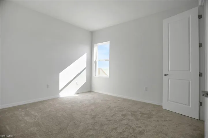 Carpeted spare room featuring baseboards