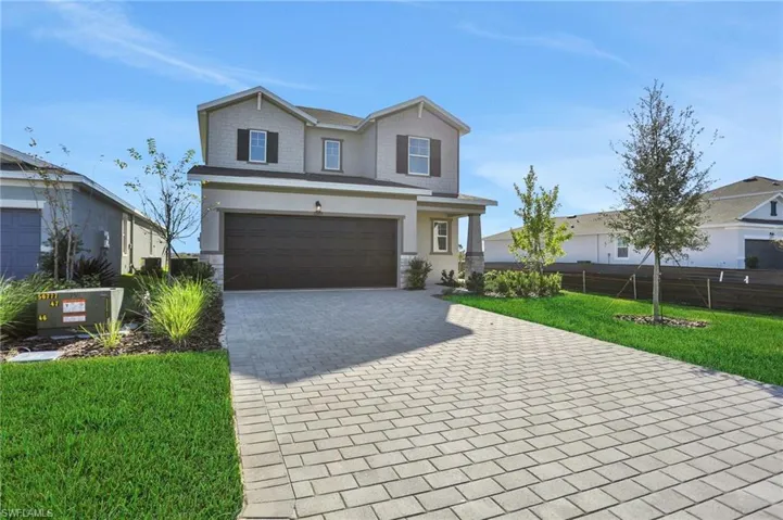 Craftsman-style house featuring decorative driveway, a garage, and stone siding