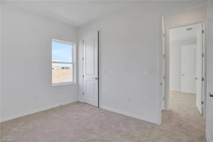Unfurnished bedroom featuring light colored carpet and baseboards