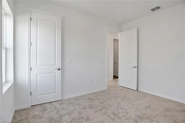 Unfurnished bedroom featuring light carpet and baseboards