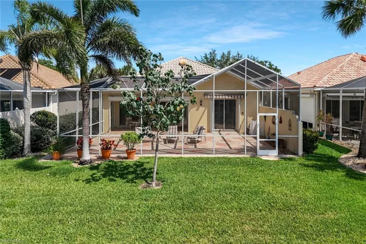 Back of house with a patio area, stucco siding, a lanai, and a yard