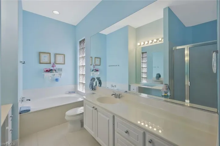 Bathroom with vanity, a stall shower, tile patterned flooring, toilet, and a garden tub