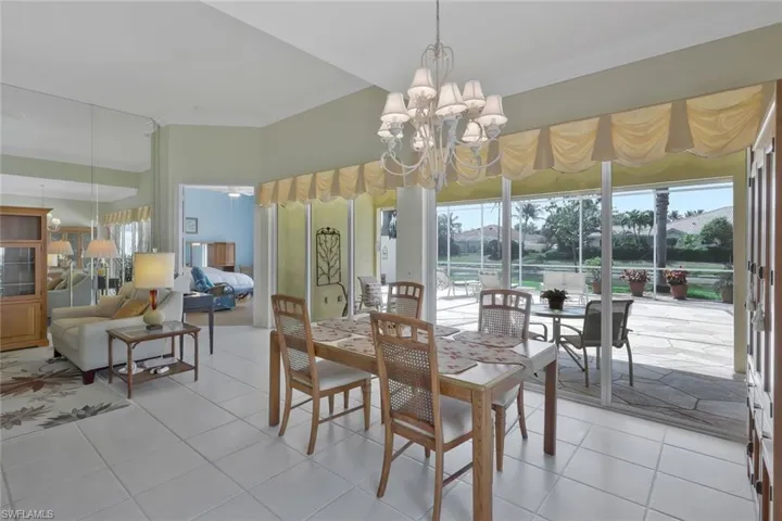 Dining space with crown molding, light tile patterned floors, plenty of natural light, and an inviting chandelier