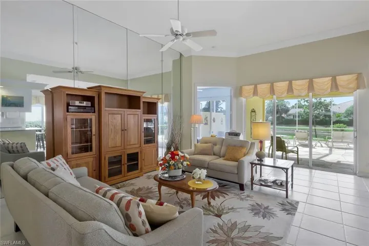 Living area featuring ornamental molding, ceiling fan, light tile patterned flooring, and a towering ceiling