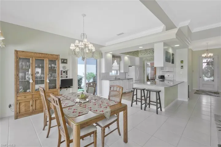 Dining area with crown molding, baseboards, an inviting chandelier, and light tile patterned flooring