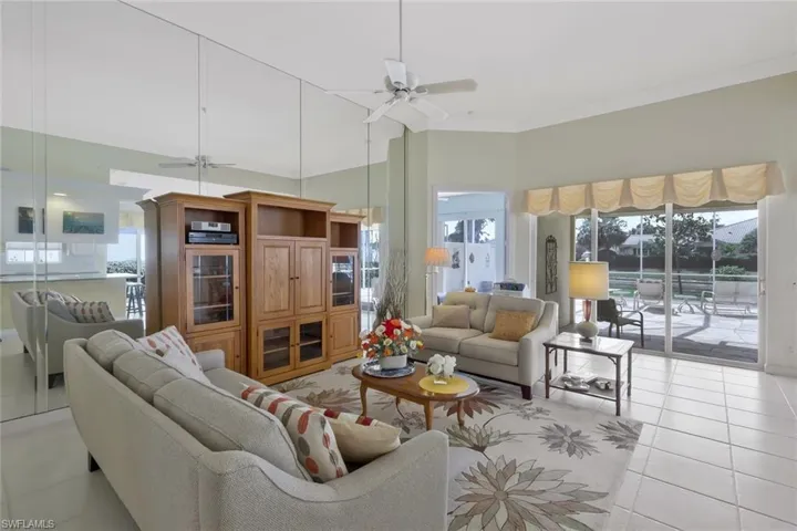 Living area with light tile patterned flooring, ornamental molding, a towering ceiling, and a ceiling fan