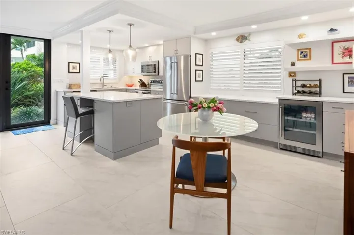 Kitchen featuring gray cabinetry, wine cooler, stainless steel appliances, a breakfast bar area, and pendant lighting