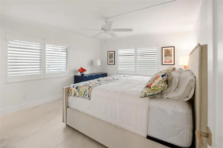 Bedroom featuring multiple windows, ornamental molding, and a ceiling fan