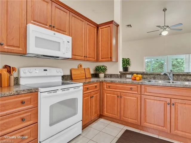 Kitchen with ceiling fan, light tile patterned flooring, sink, and white appliances