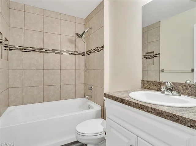 Full bathroom featuring tiled shower / bath, vanity, and toilet