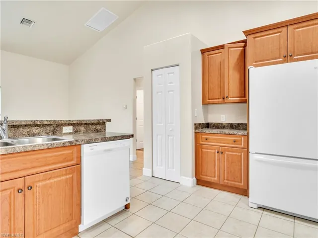 Kitchen with white appliances, high vaulted ceiling, sink, and light tile patterned floors