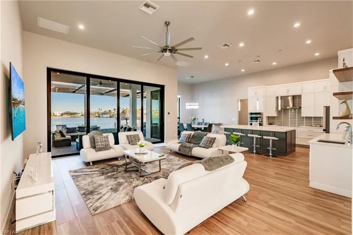 Living area with recessed lighting, ceiling fan, and light wood-style flooring