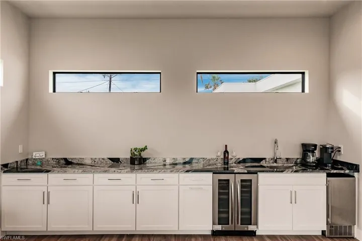 Indoor wet bar featuring beverage cooler and stainless steel refrigerator