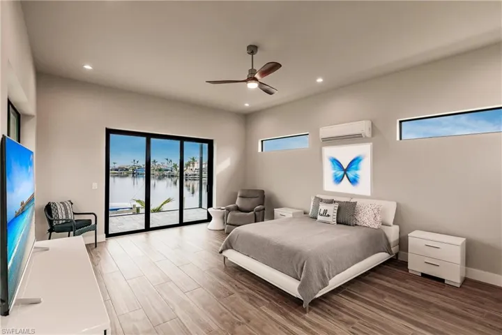 Bedroom with access to exterior, wood finished floors, recessed lighting, a water view, and a wall mounted air conditioner
