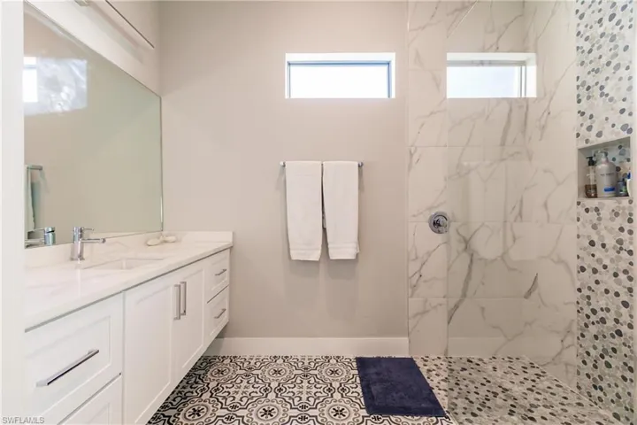 Bathroom with vanity and a marble finish shower