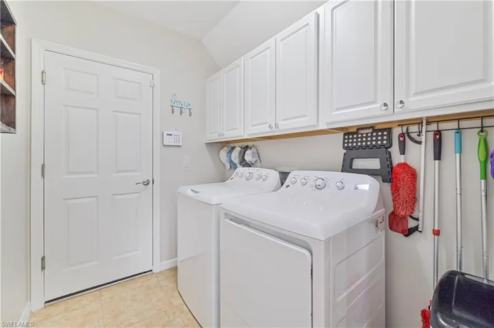 Laundry room with light tile patterned floors, independent washer and dryer, and cabinets