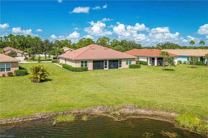Back of house featuring a water view and a lawn