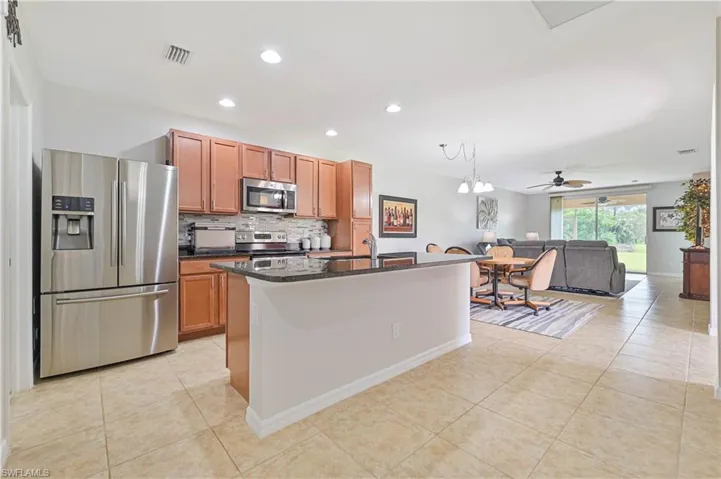 Kitchen with light tile patterned floors, stainless steel appliances, ceiling fan, and decorative backsplash