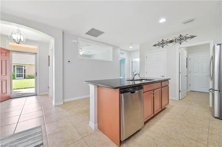 Kitchen with stainless steel appliances, sink, hanging light fixtures, a center island with sink, and light tile patterned flooring