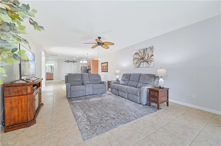 Tiled living room with ceiling fan with notable chandelier
