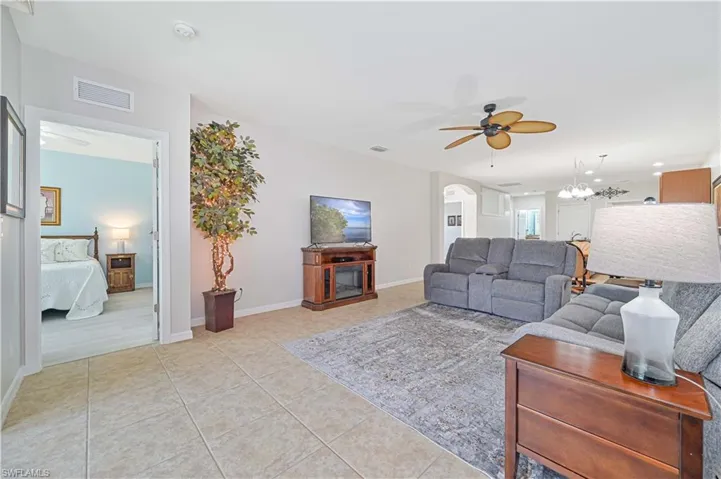 Tiled living room featuring ceiling fan with notable chandelier