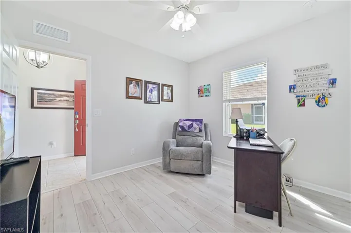 Office area with ceiling fan with notable chandelier and light wood-type flooring