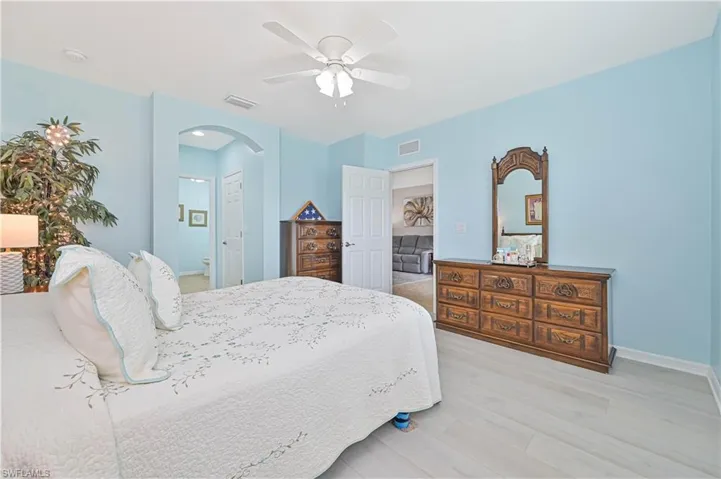 Bedroom with connected bathroom, ceiling fan, and light hardwood / wood-style floors