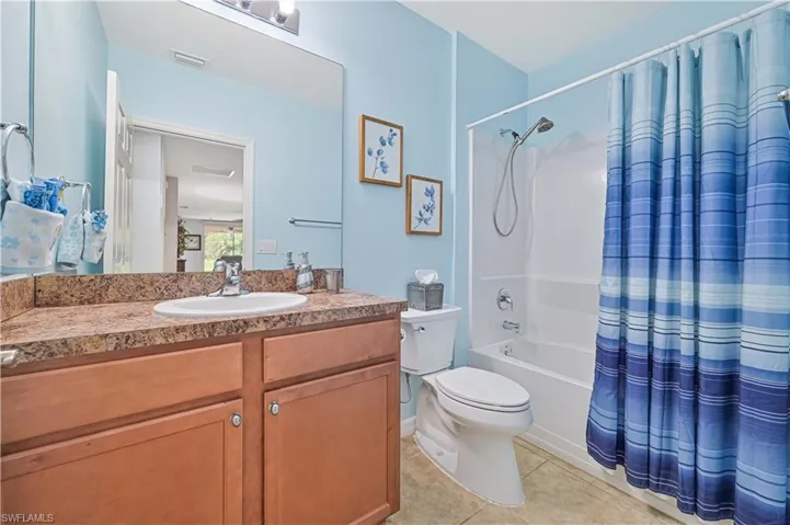 Full bathroom with vanity, toilet, tile patterned floors, and shower / bath combination with curtain