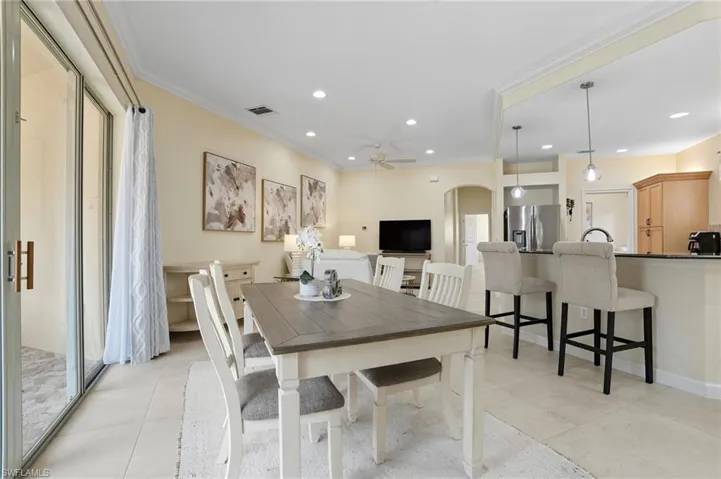 Dining room featuring arched walkways, ornamental molding, recessed lighting, light tile patterned floors, and a ceiling fan
