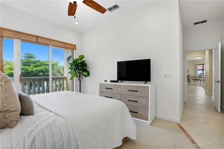 Bedroom featuring inlaid floor details, access to exterior, light tile patterned floors, arched walkways, and a ceiling fan