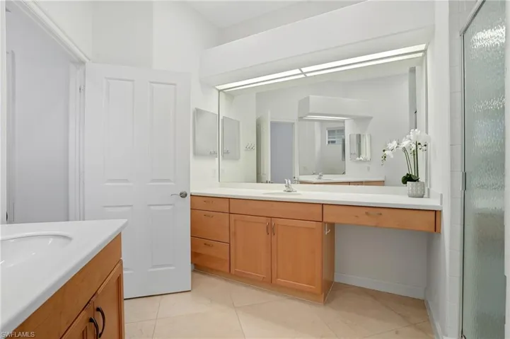 Bathroom with a shower stall, two vanities, and light tile patterned floors