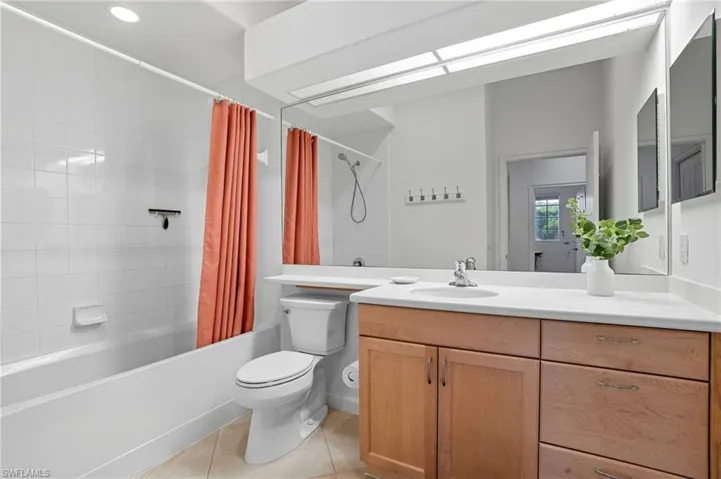 Bathroom featuring shower / bath combo, light tile patterned floors, and vanity