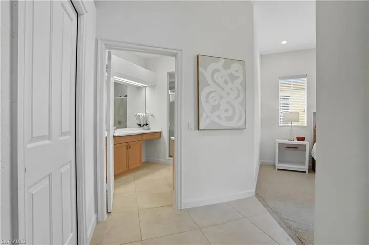 Corridor with light tile patterned floors and light carpet