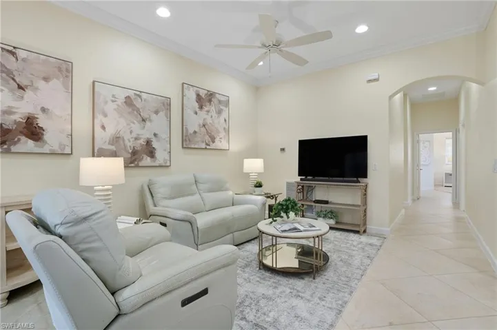 Living area with crown molding, arched walkways, light tile patterned floors, recessed lighting, and a ceiling fan