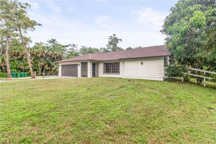 Back of house with a garage and a lawn
