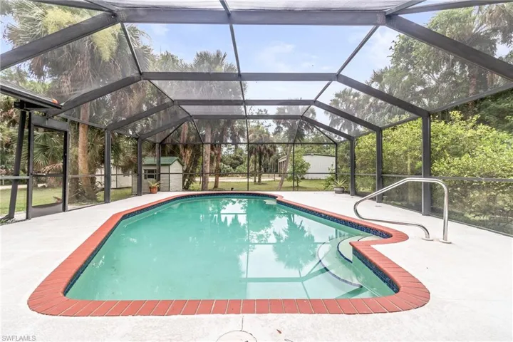 View of swimming pool with a patio area, a storage unit, and glass enclosure