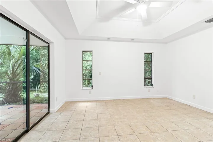Spare room with a raised ceiling, light tile patterned floors, and ceiling fan