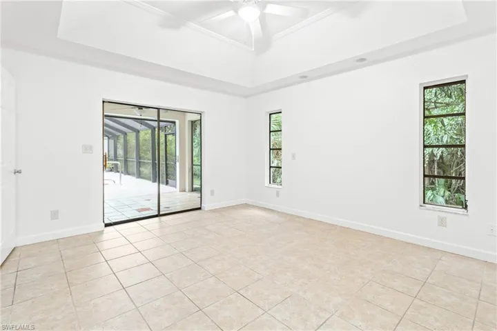 Spare room featuring light tile patterned flooring, a raised ceiling, a wealth of natural light, and ceiling fan