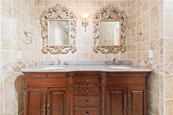 Bathroom featuring dual vanity and tile walls