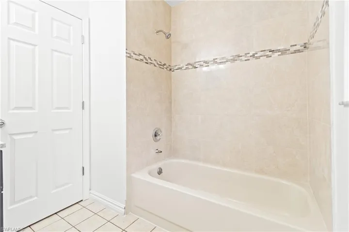 Bathroom featuring tiled shower / bath and tile patterned flooring