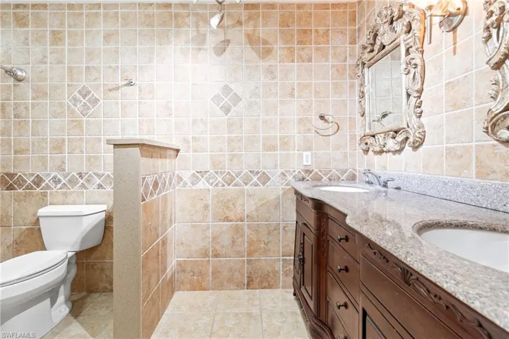 Bathroom with tile walls, tile patterned floors, and double sink vanity