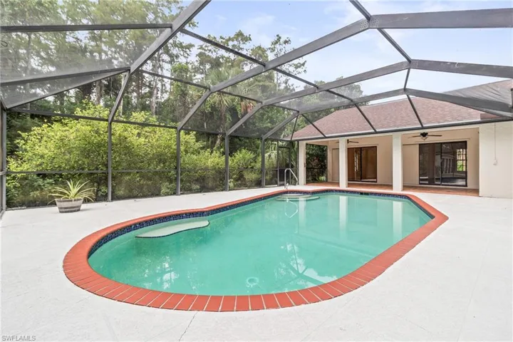 View of pool with a patio, glass enclosure, and ceiling fan