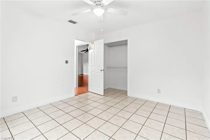 Unfurnished bedroom with light tile patterned flooring, a closet, and ceiling fan