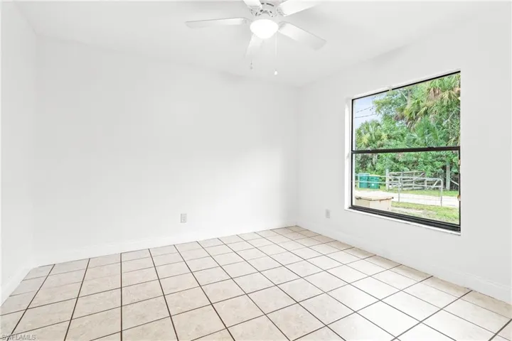 Tiled spare room featuring a healthy amount of sunlight and ceiling fan